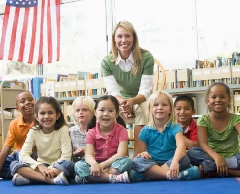 Kindergarten teacher sitting with children in library