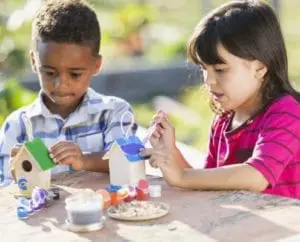 Multi-ethnic children painting little wooden bird houses